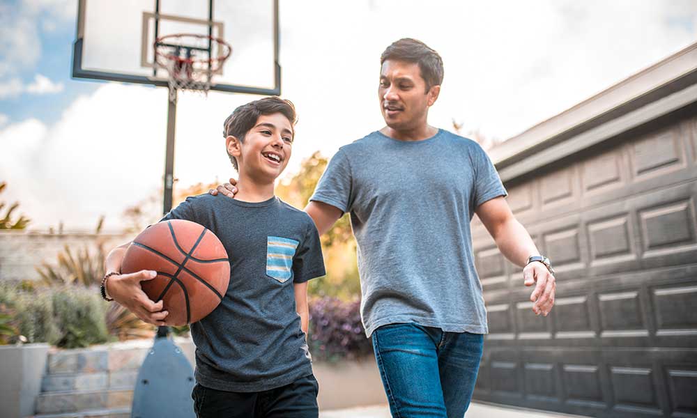 father and son playing basketball in backyard