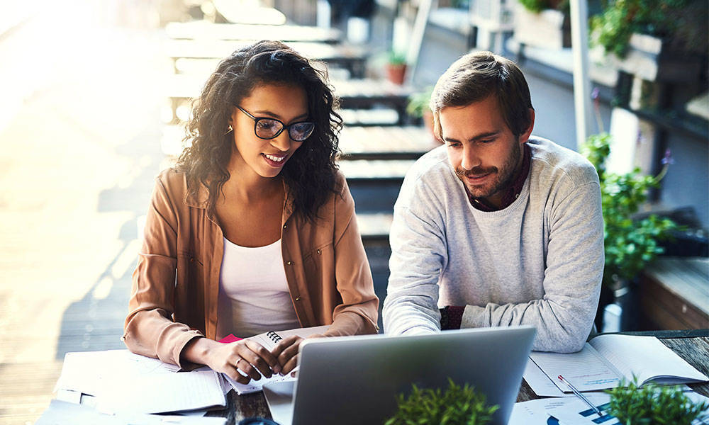 Two people working on their finances at a coffee shop.