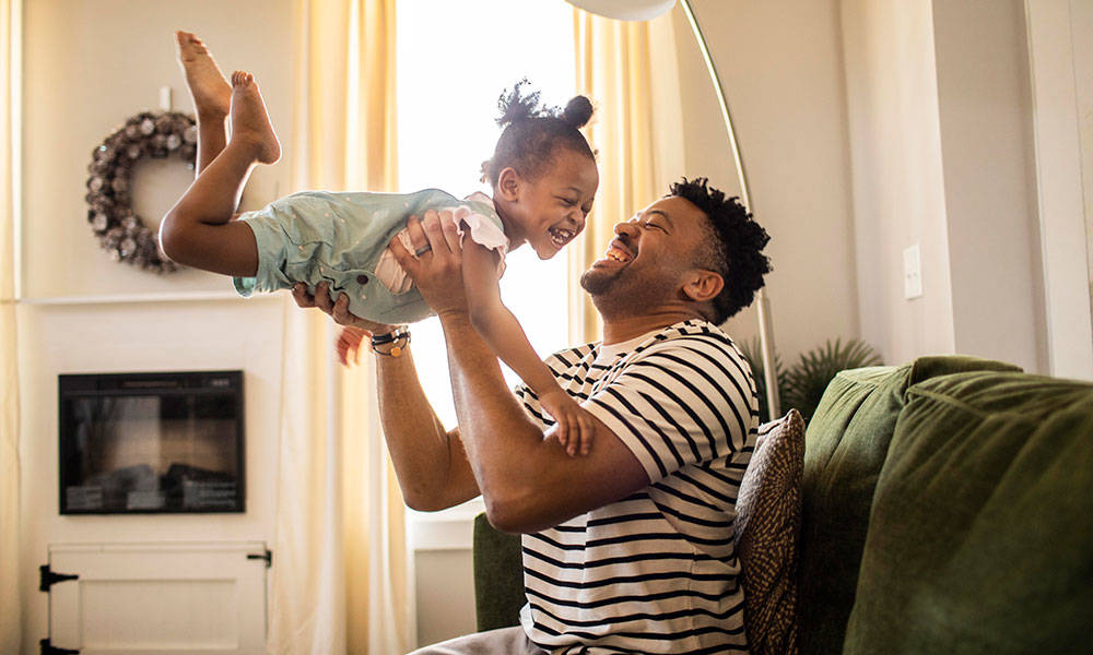 father lifting up his daughter while both smiling