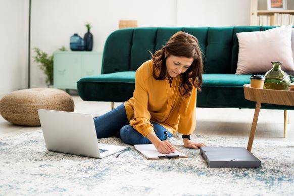 Woman on floor of home paying bills