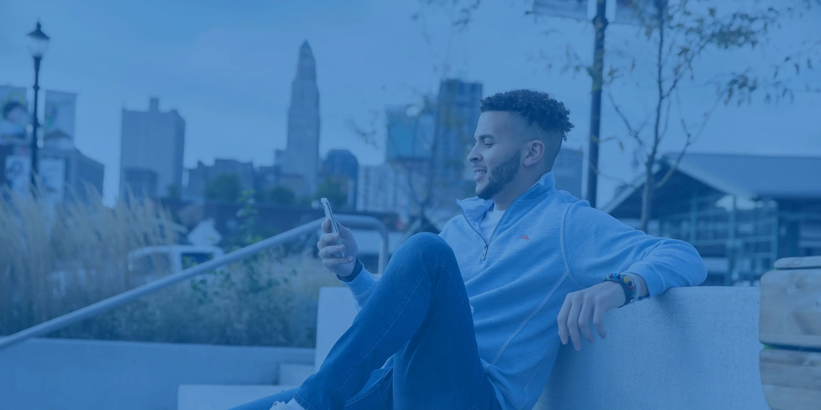 Person Looking at Phone with Blue Overlay City Background